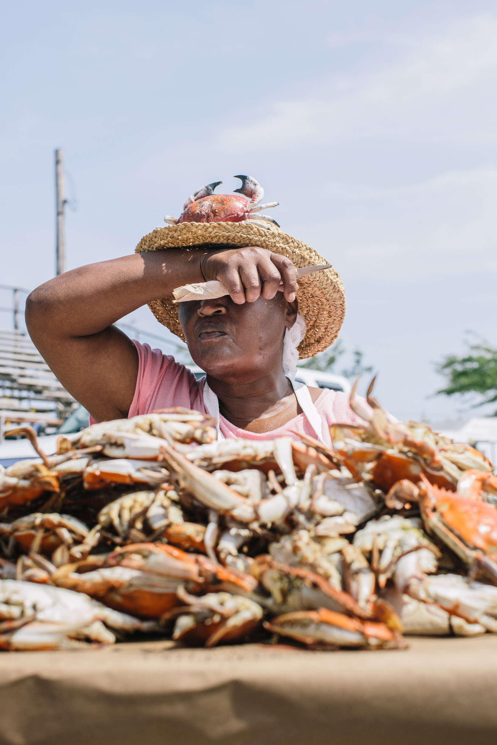 woman picks pile of blue crabs