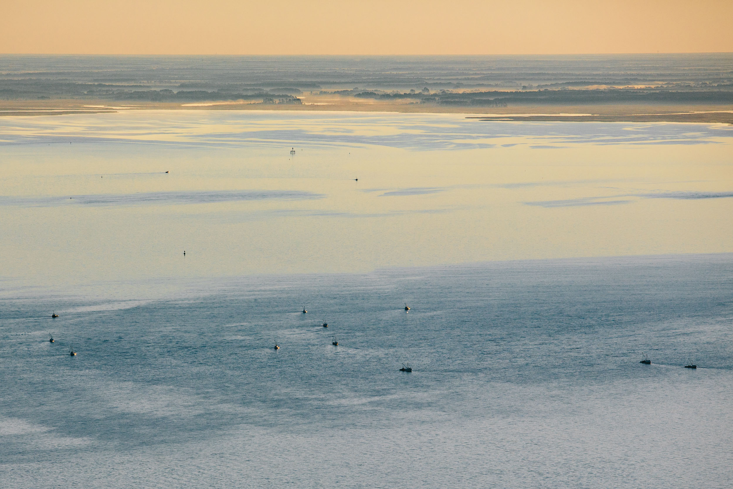 aerial photo of Crab boats at sunrise head out into the bay