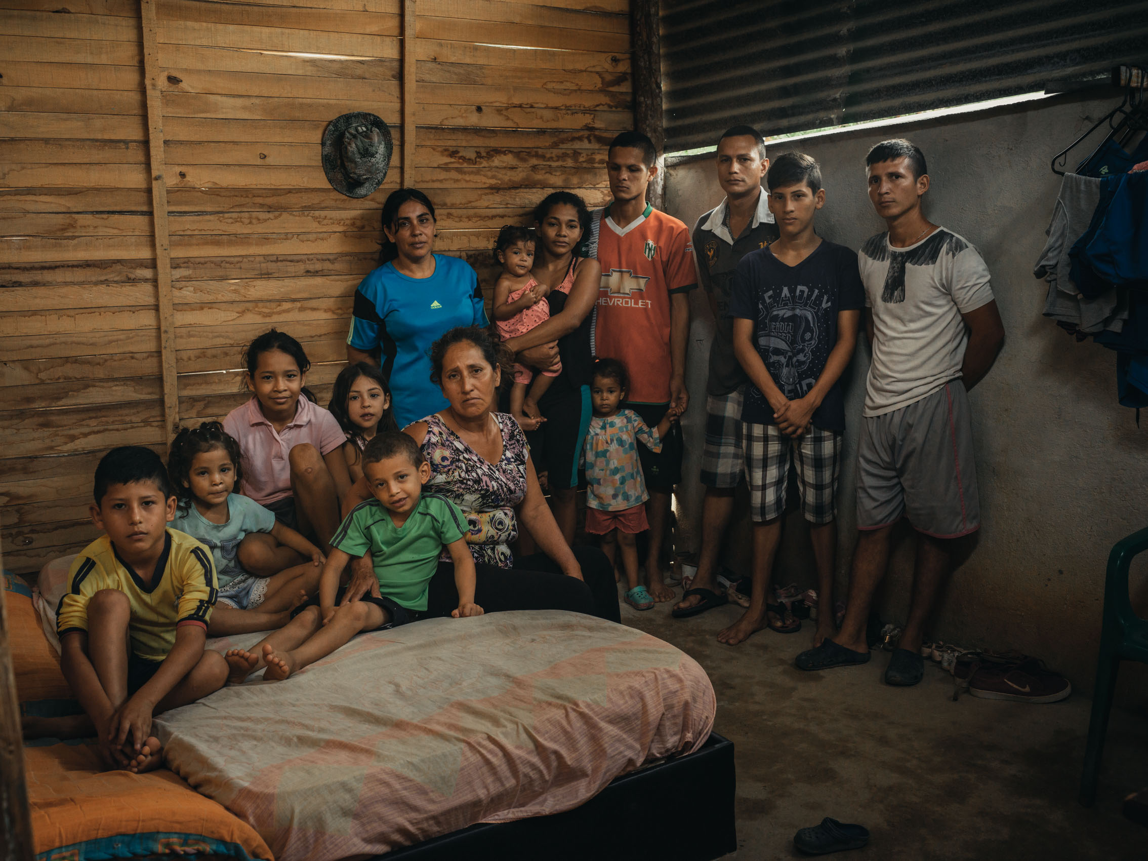 A portrait of a Venezuelan family in their bedroom where all 14 sleep