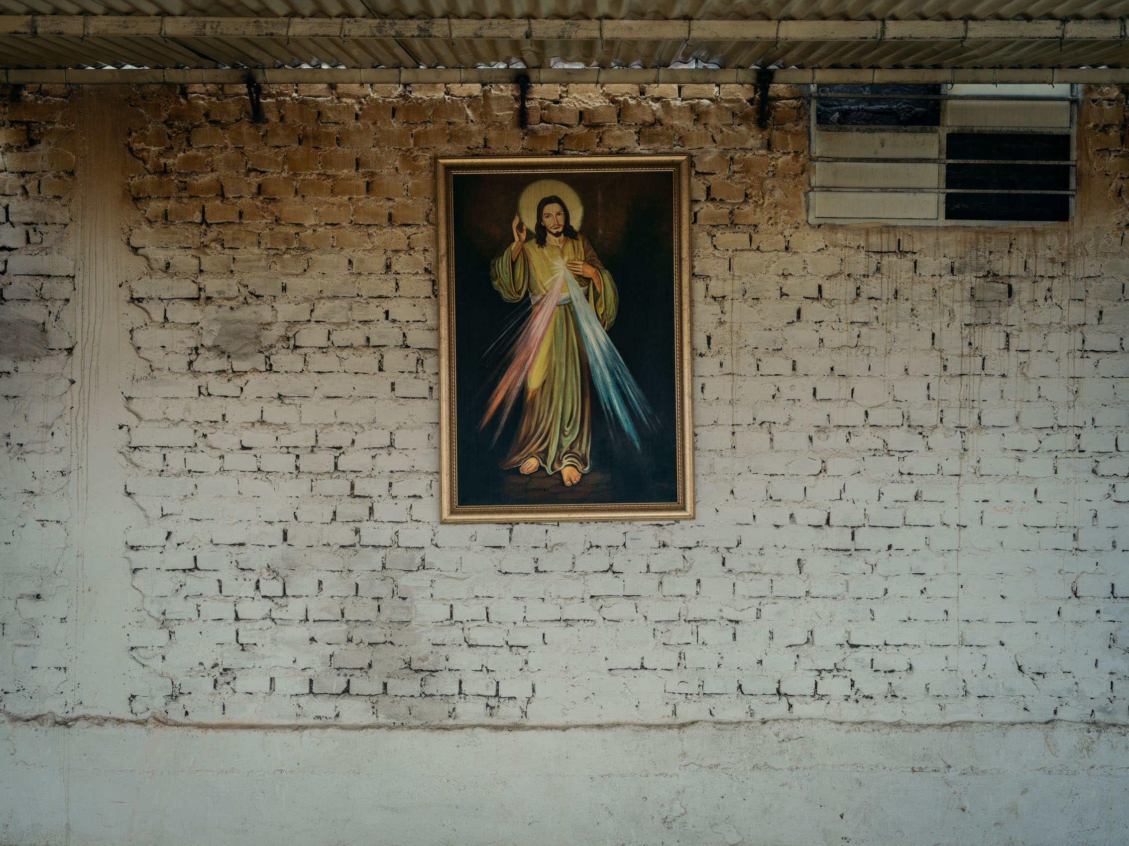 A painting of Jesus hangs on a white brick wall