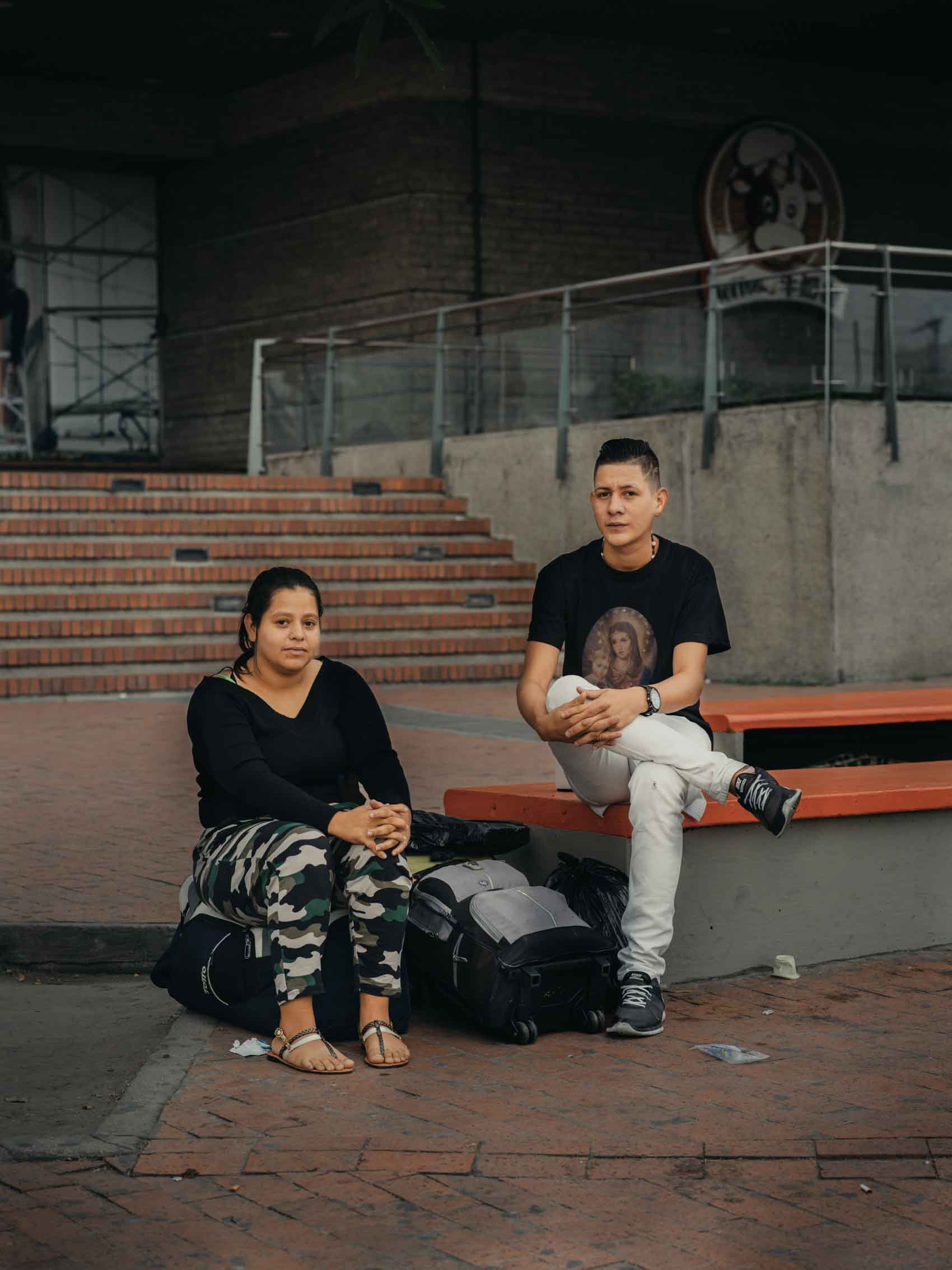portrait of friends sitting on bench outside mall 