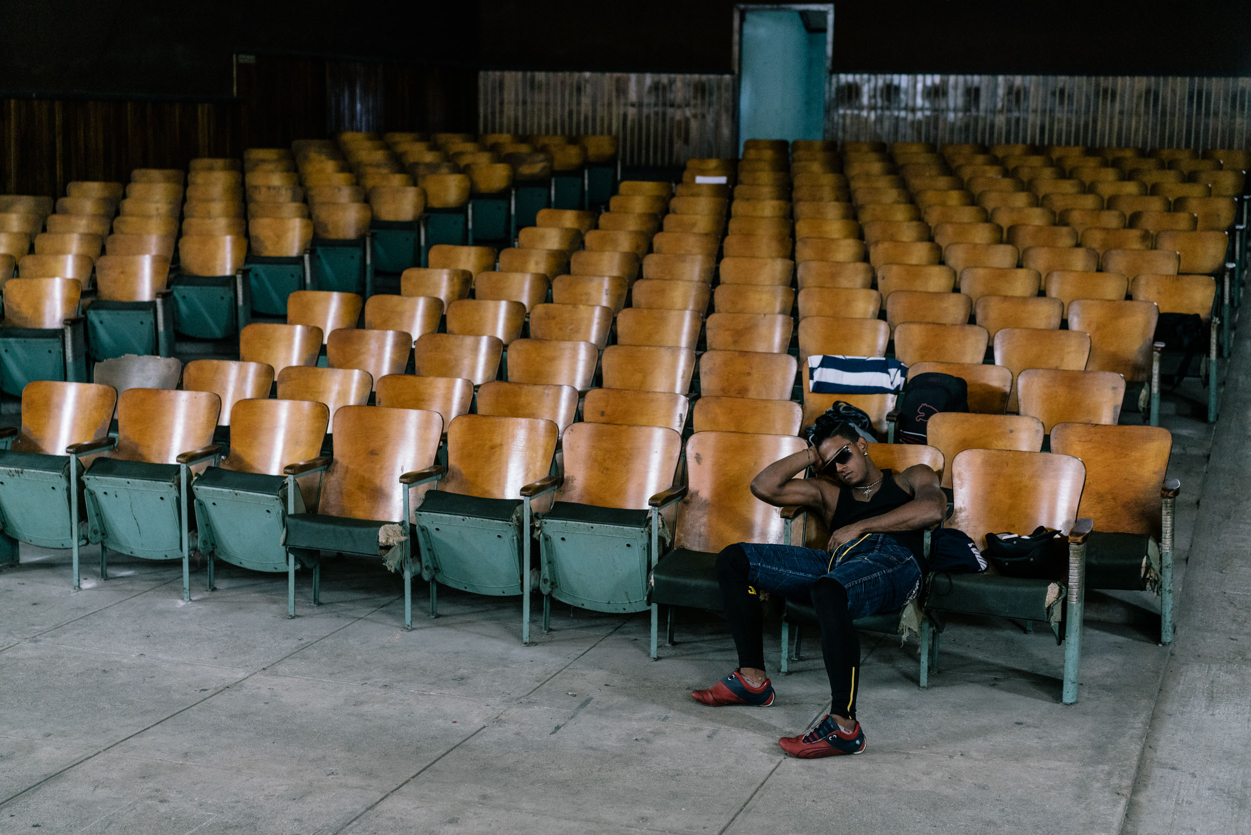 man asleep in chair in empty theater seats