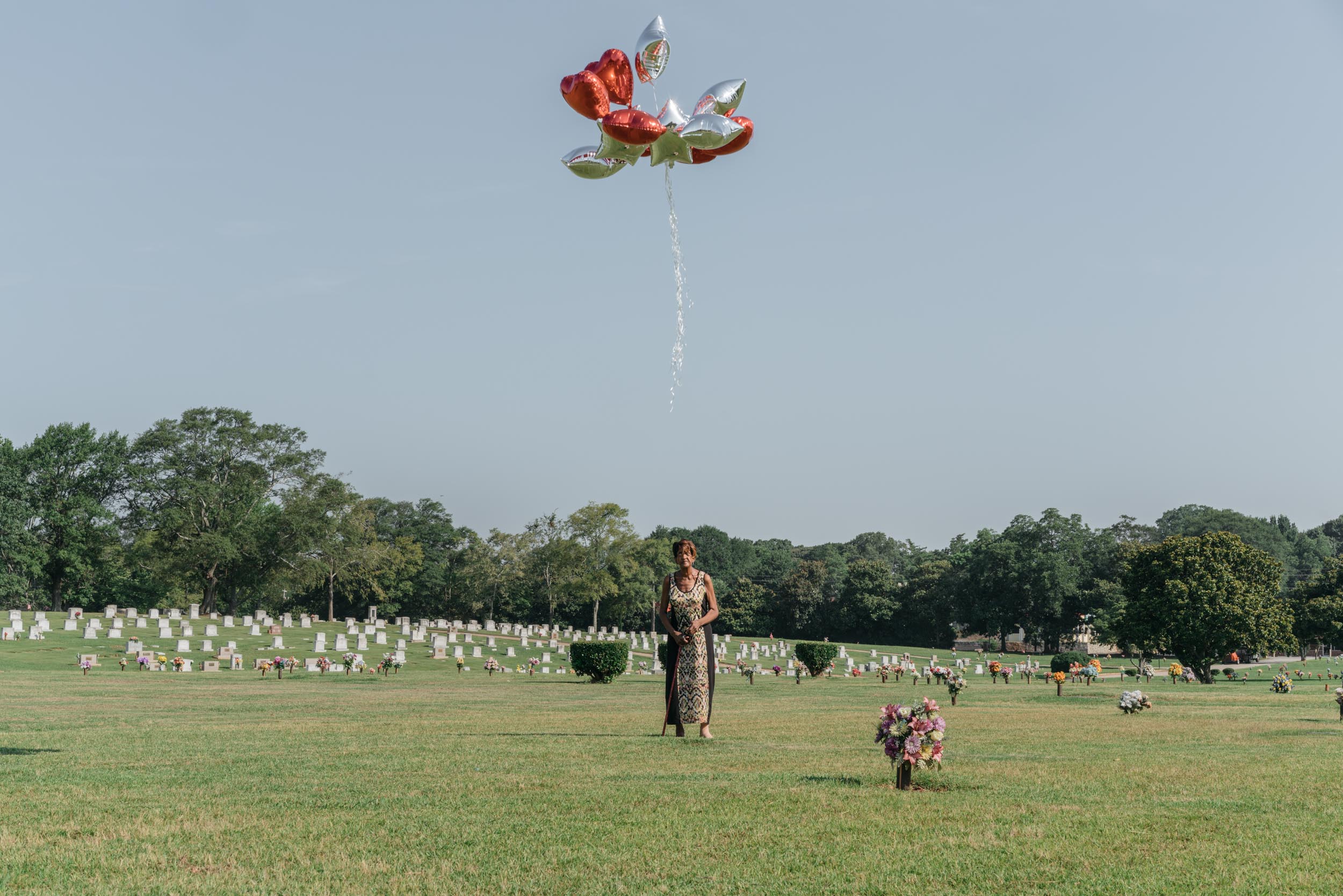 woman holding balloons at graveyard